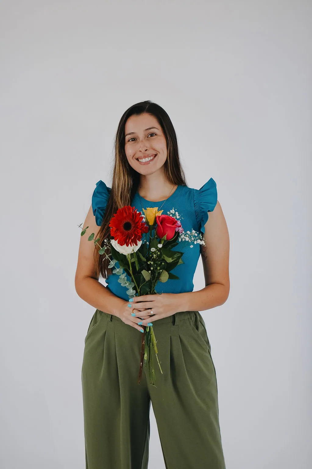 Jaclyn holding a bouquet of fresh flowers against a soft studio backdrop